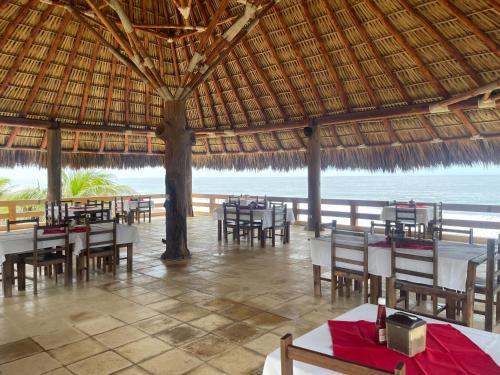 a restaurant with tables and chairs and a straw umbrella at Hotel Pazifico en Monterrico in Monterrico