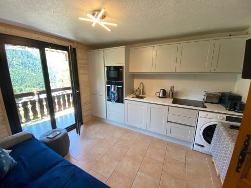 un salon avec un canapé bleu dans une cuisine dans l'établissement Appartement cosy à Châtel avec parking privé, proche centre et télécabine. Animaux non admis. - FR-1-693-45, à Châtel