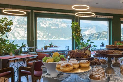 una mesa con un montón de pan y pasteles en ella en Hotel Paradiso Conca d'Oro, en Nago-Torbole