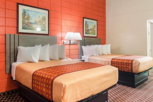 two beds in a hotel room with red walls at Rodeway Inn in Nashville