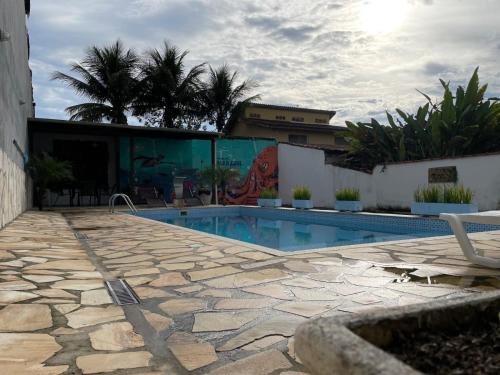 a swimming pool with a patio and a building at Pousada Mar Azul in Paraty