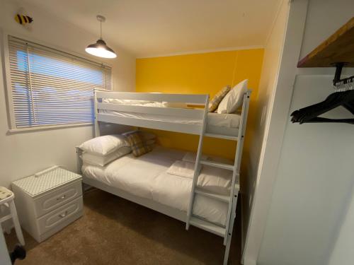 a room with two bunk beds and a couch at East Coast Chalets, Bee’s Knees @ California Sands in Scratby