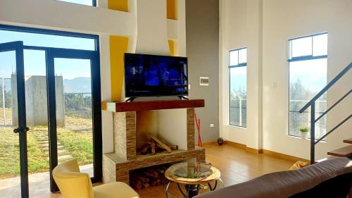 a living room with a television and a fireplace at Casa de Campo Mirador de la Retama in Cajamarca