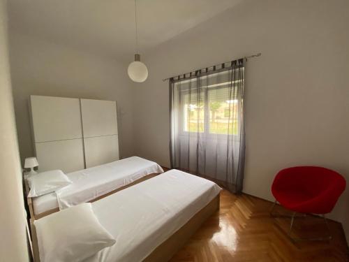 a bedroom with two beds and a red chair at Apartment Vodnjan in Vodnjan
