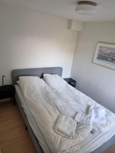 a bed with white sheets and two pillows on it at Apartment 7 min from the airport in Bergen