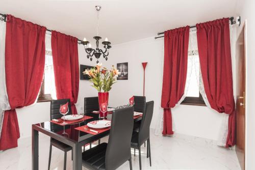 a dining room with red curtains and a table with chairs at Apartments Paris in Umag