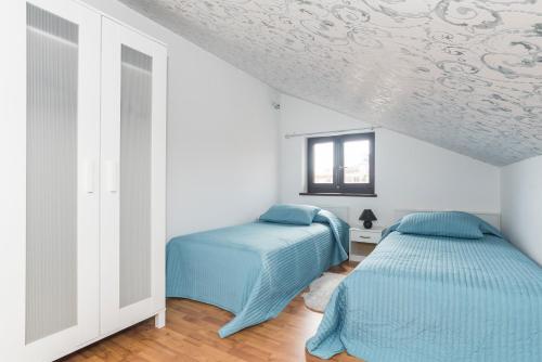 two beds in a white room with blue sheets at Apartments Paris in Umag