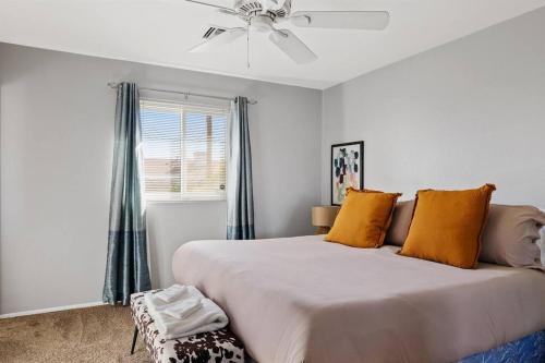 Schlafzimmer mit einem Bett mit orangefarbenen Kissen und einem Deckenventilator in der Unterkunft Southwestern Style Home Near Old Town Scottsdale in Scottsdale