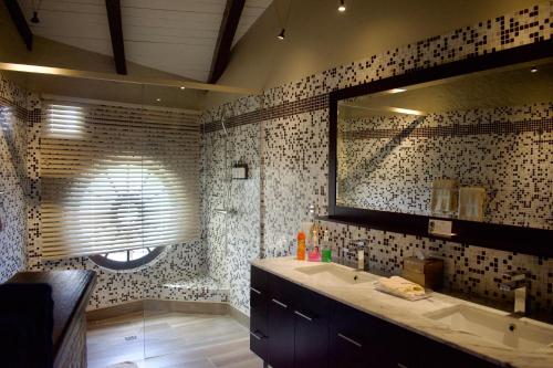 a bathroom with a sink and a large mirror at Secret Harbour Boutique Hotel and Marina in Lance aux Épines