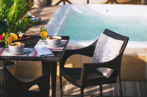 a table and chairs with food on it next to a pool at Secret Harbour Boutique Hotel and Marina in Lance aux Épines