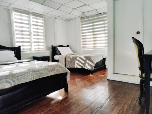 a bedroom with two beds and windows and wooden floors at Hotel Muros Quito in Quito