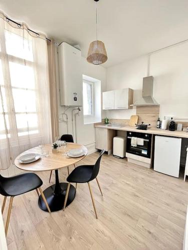 une cuisine avec une table et des chaises dans une pièce dans l'établissement L'Aventurine - Romans, à Romans-sur-Isère