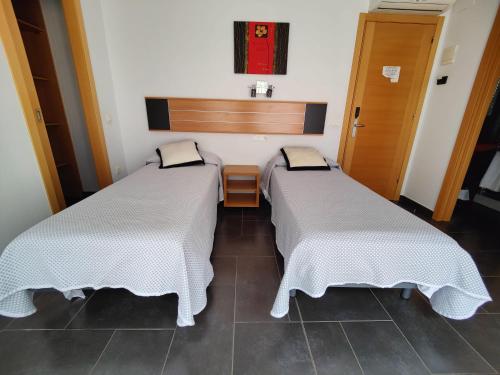 two beds sitting next to each other in a room at Hostal Manel in Pineda de Mar