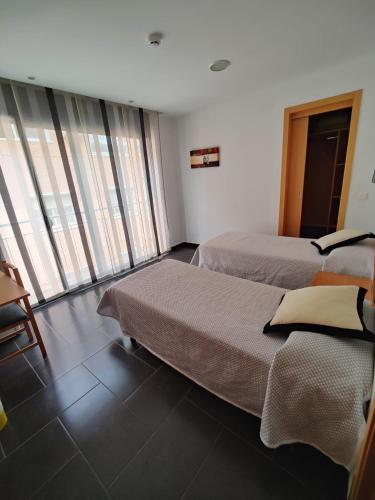 two beds in a hotel room with windows at Hostal Manel in Pineda de Mar
