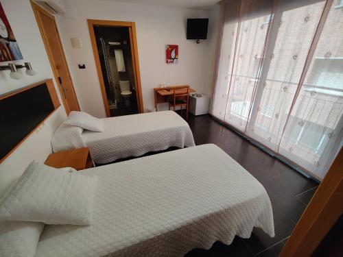 a hotel room with two beds and a window at Hostal Manel in Pineda de Mar