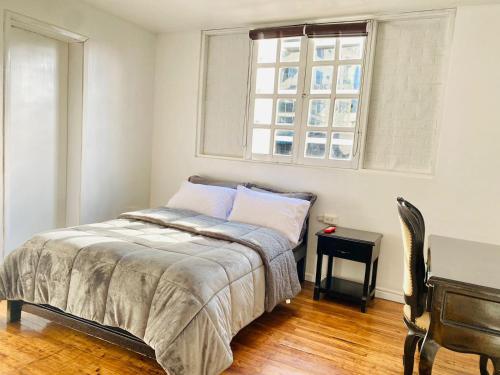 a bedroom with a bed and a desk and a window at Hotel Muros Quito in Quito