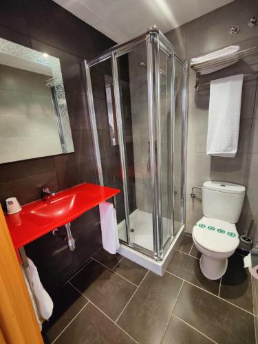 a bathroom with a shower and a toilet and a red sink at Hostal Manel in Pineda de Mar