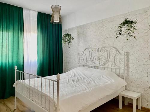 ein weißes Kinderbett in einem Schlafzimmer mit grünen Vorhängen in der Unterkunft Union Experience - City Center in Timişoara