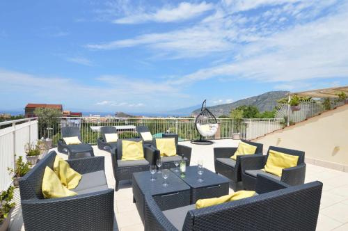 eine Terrasse mit gelben Kissen, Tischen und Stühlen in der Unterkunft La Terrazza Family Holidays, Sorrento Coast in Sant'Agnello