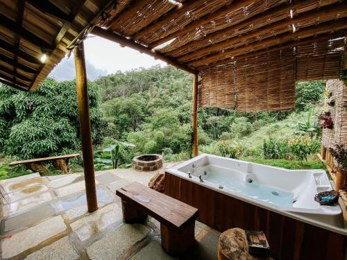 a bath tub in a room with a view at Sítio Balango: Seu refúgio em Domingos Martins. Chalés para casais e casa para grupo de pessoas in Domingos Martins