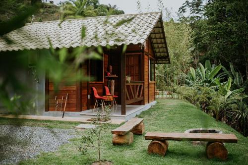 a small wooden cabin with a bench and a table at Sítio Balango: Seu refúgio em Domingos Martins. Chalés para casais e casa para grupo de pessoas in Domingos Martins
