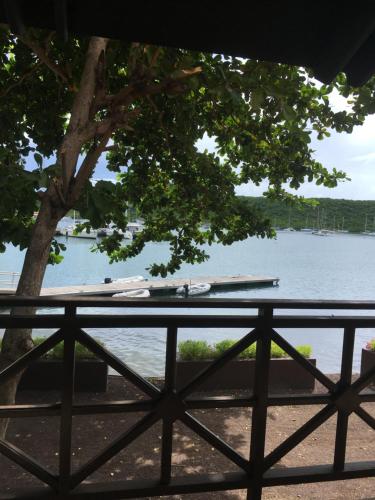 a picnic table next to a lake with a tree at Secret Harbour Boutique Hotel and Marina in Lance aux Épines