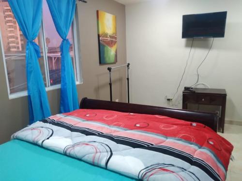 um quarto com uma cama com cortinas azuis e uma televisão em Departamentos velasco em Tijuana