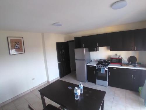 a kitchen with black cabinets and a table and a stove at Departamentos velasco in Tijuana
