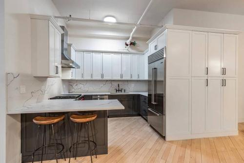 a kitchen with white cabinets and a kitchen island with bar stools at Luxurious 2 Bedroom Loft Entire Apartment in New York