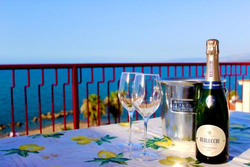 Una botella de vino y dos copas en una mesa. en Le Terrazze sulle Eolie, en Caronia Marina