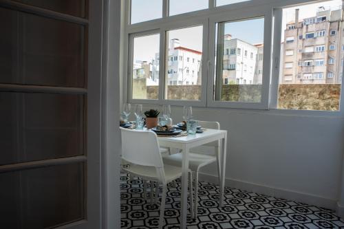 a white table and chairs in a room with windows at Succeed Campo Pequeno Suites in Lisbon