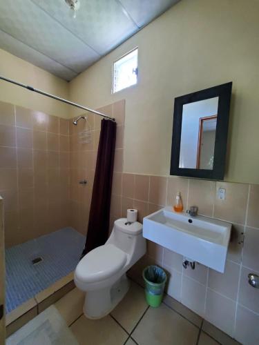 a bathroom with a toilet and a sink and a shower at Dylan’s Surf Inn in La Libertad