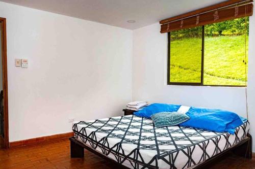 a bedroom with a bed with blue sheets and a window at Espectacular casa campestre in Pereira
