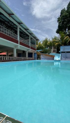 Hotel y Balneario Villa Paraíso في Catacamas: مسبح كبير من الماء الأزرق أمام مبنى