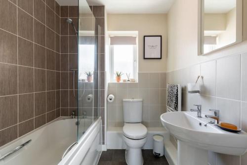 a bathroom with a toilet and a sink and a bath tub at Stylish 2 Bed Flat near Station, Parking, Sleeps 6 in Spon End