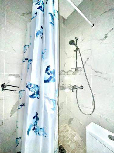 La salle de bains est pourvue d'une douche avec un rideau de douche bleu et blanc. dans l'établissement Dream Dwell Paris- The 6th district Paris Historical apartment near Montparnasse, à Paris