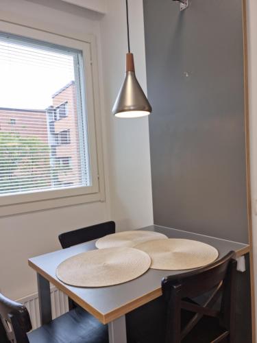a dining room table with two chairs and a lamp at Viihtyisä saunallinen kaksio lentokentän lähellä in Vantaa