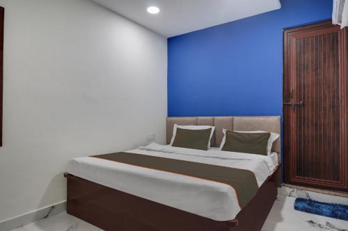 a bedroom with a large bed with a blue wall at Collection O Hotel Miraaz in Gwalior