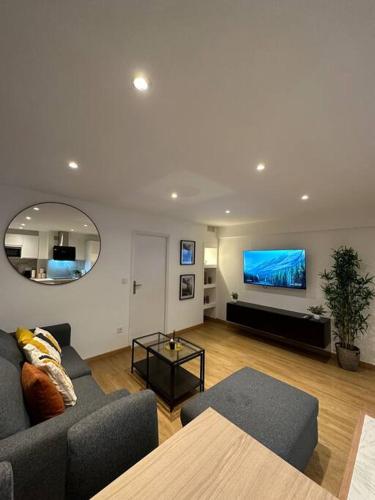 a living room with a couch and a flat screen tv at Charmant Appart Métro Proche Confort in Bagnolet