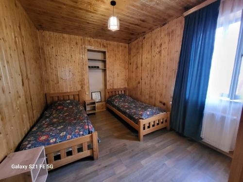 twee bedden in een kamer met houten wanden bij Peak House in Kazbegi