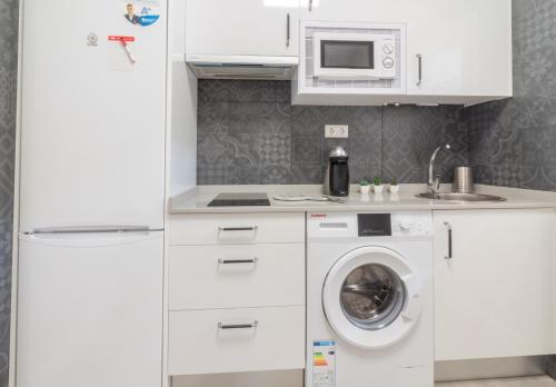 a kitchen with a washing machine and a microwave at Apart Infante Casco Histórico de Ribadesella VUT-1322-AS in Ribadesella