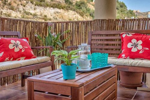 - une table basse en bois sur une terrasse avec 2 chaises dans l'établissement ApartRincón Sorolla, à Rincón de la Victoria