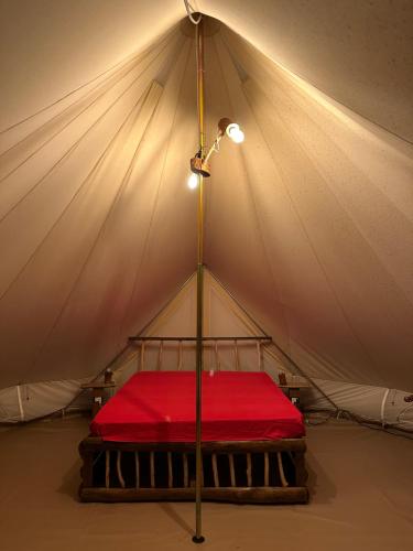 a bed in a tent with a red sheet at Il Favogoloso in Alatri