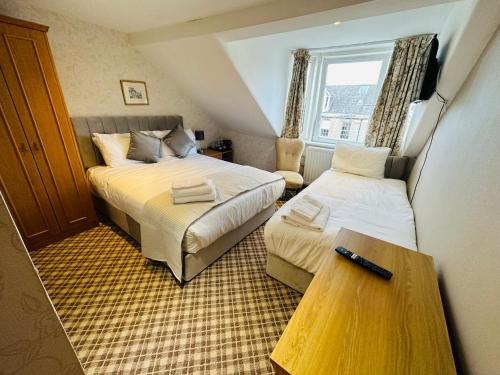 a small room with two beds and a table at Abbotsford Guest House in Edinburgh