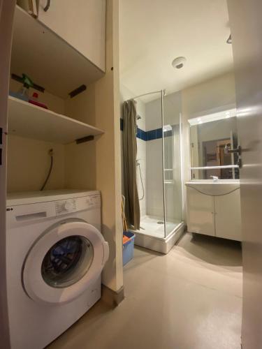 La salle de bains est pourvue d'une douche et d'un lave-linge blanc. dans l'établissement Appartement idéalement situé wifi disponible, à Cauterets