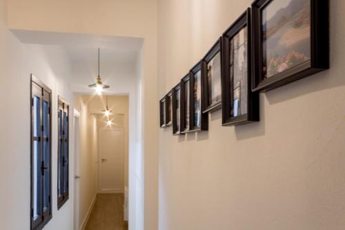 a hallway with a row of framed pictures on the wall at Apart Infante Casco Histórico de Ribadesella VUT-1322-AS in Ribadesella