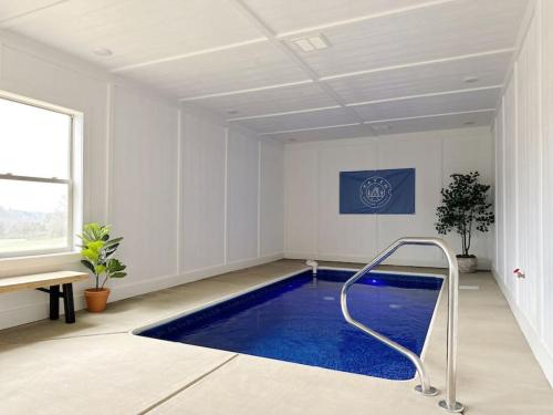 a swimming pool in a white room with a blue floor at Wildwood Retreat Indoor Pool Hot Tub Game Area in Pigeon Forge