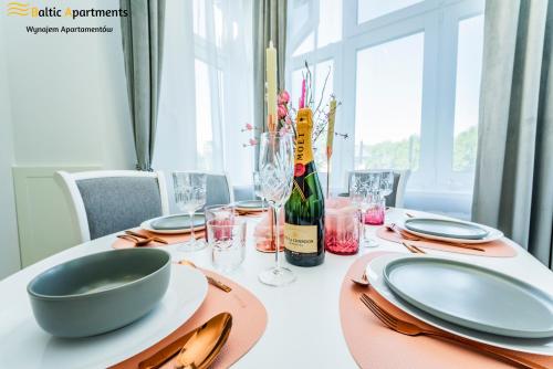 a dining table with a bottle of wine and glasses at Baltic Apartments - Willa Carmen DeLuxe in Świnoujście