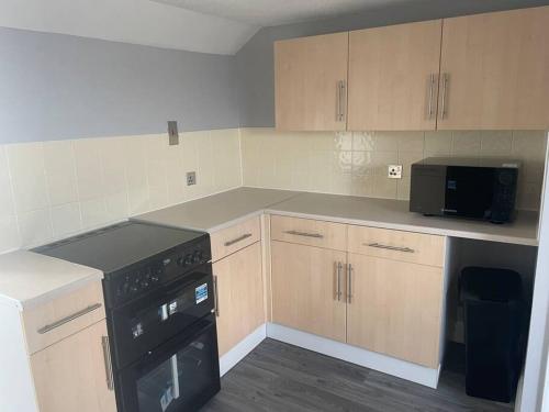 a kitchen with wooden cabinets and a black stove at Large self contained 1 bedroom flat with parking. in Plymouth
