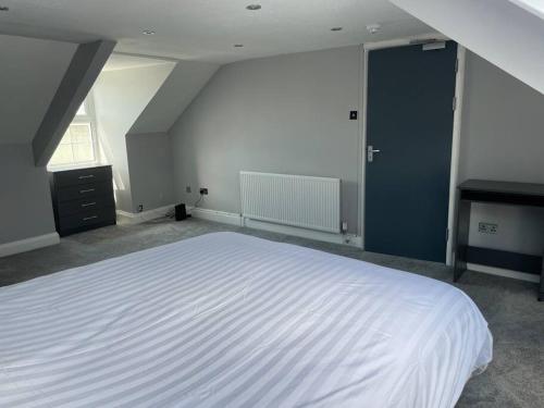 a bedroom with a large white bed and a blue door at Large self contained 1 bedroom flat with parking. in Plymouth